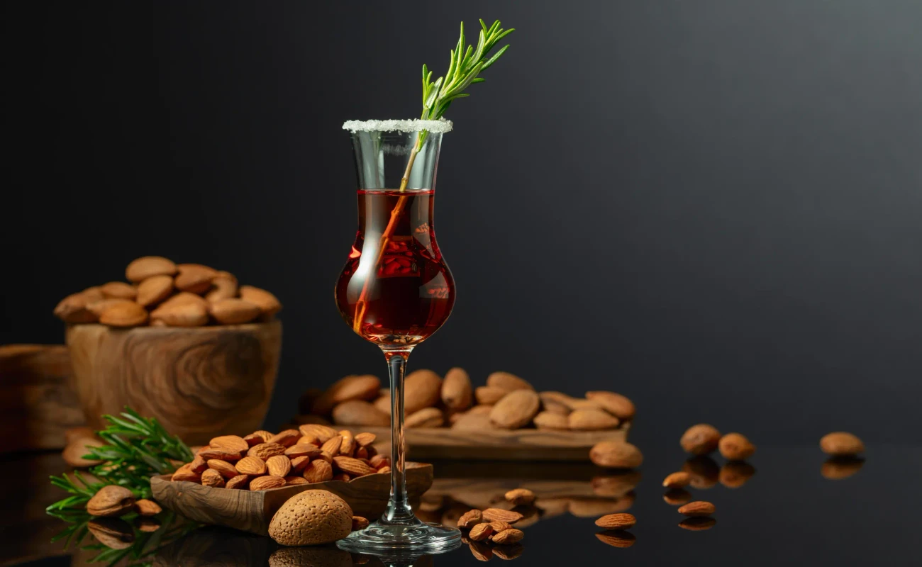 Strong alcoholic Italian liqueur Amaretto with almonds nuts on a black background. Copy space.