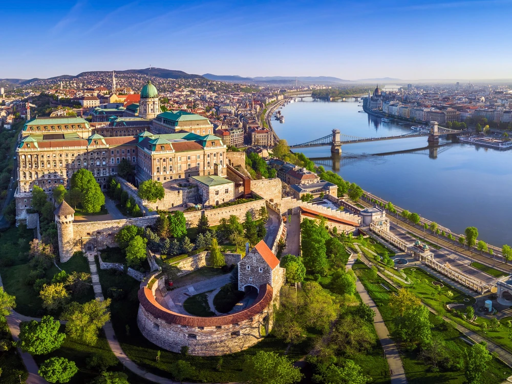 Budapest, Hungary - Aerial panoramic skyline view of Buda Castle Royal Palace with Szechenyi Chain Bridge, Hungarian Parliament and Matthias Church at sunrise with clear blue sky
