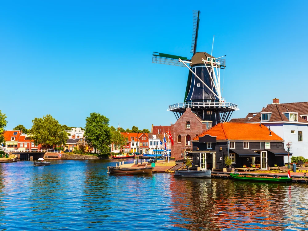 Scenic summer view of the Old Town architecture, mill and canal embankment in Haarlem, Netherlands