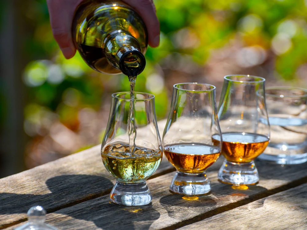 Tasting of scotch single malt whisky from Islay island, most intensely flavoured of all whiskies in Scotland on old garden table in sunny day