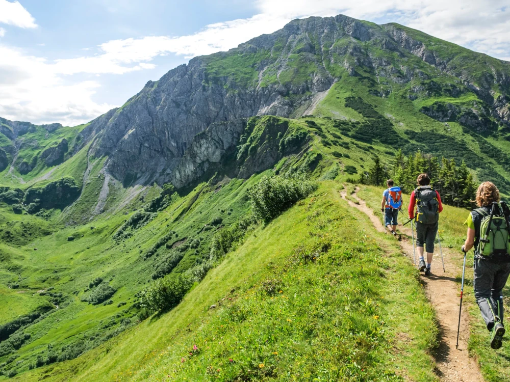 Wanderer sind im Bereich sind rund um die Erlebnisberge Kanzelwand und Fellhorn in der Grenzregion Oberallgäu/Kleinwalsertal unterwegs und genießen die herrliche Natur an einem Sommermorgen.