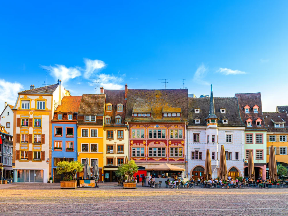 Mulhouse cityscape, typical houses colorful buildings and street restaurant outdoor café on Place de la Reunion square in old town Mulhouse city historic centre, Alsace Grand Est region, France