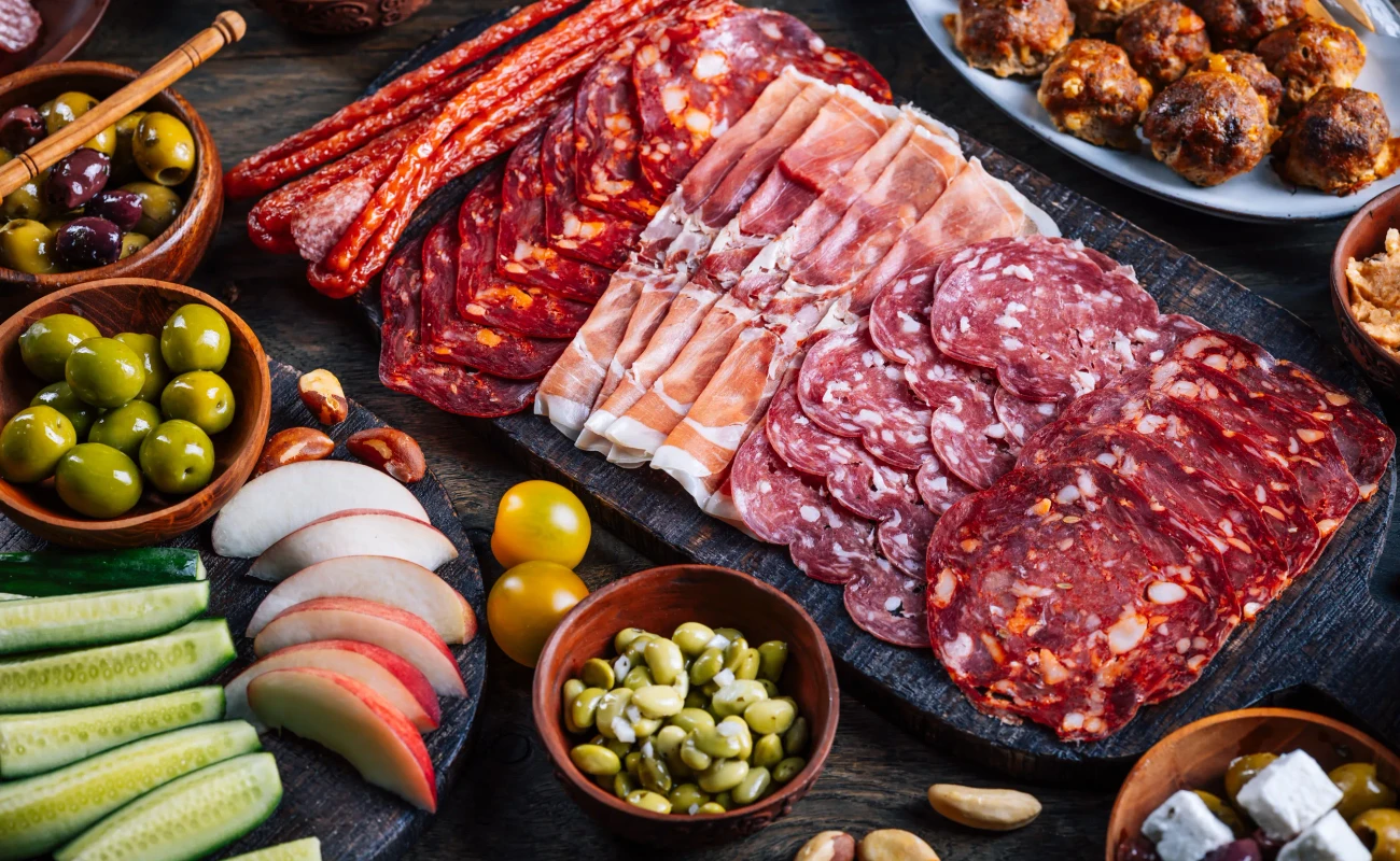 Assortment of cured meats and antipasti served on a rustic wooden board