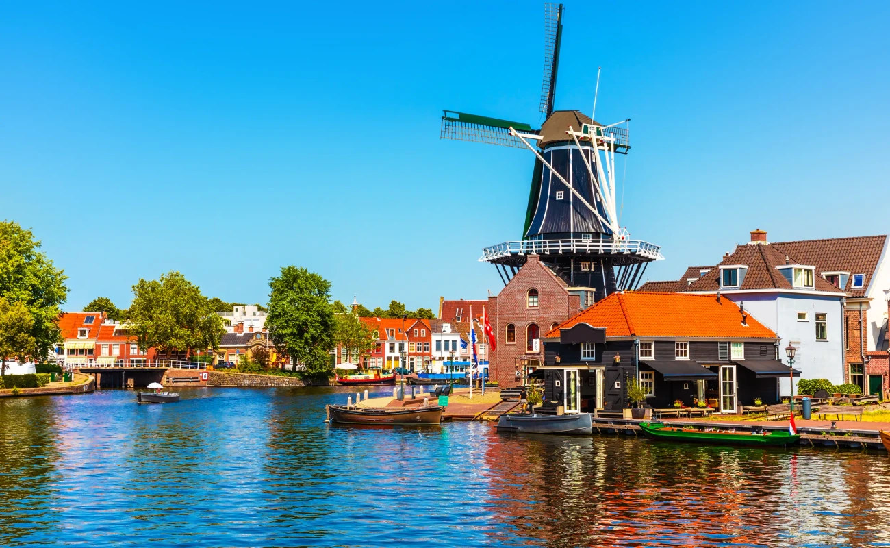 Scenic summer view of the Old Town architecture, mill and canal embankment in Haarlem, Netherlands