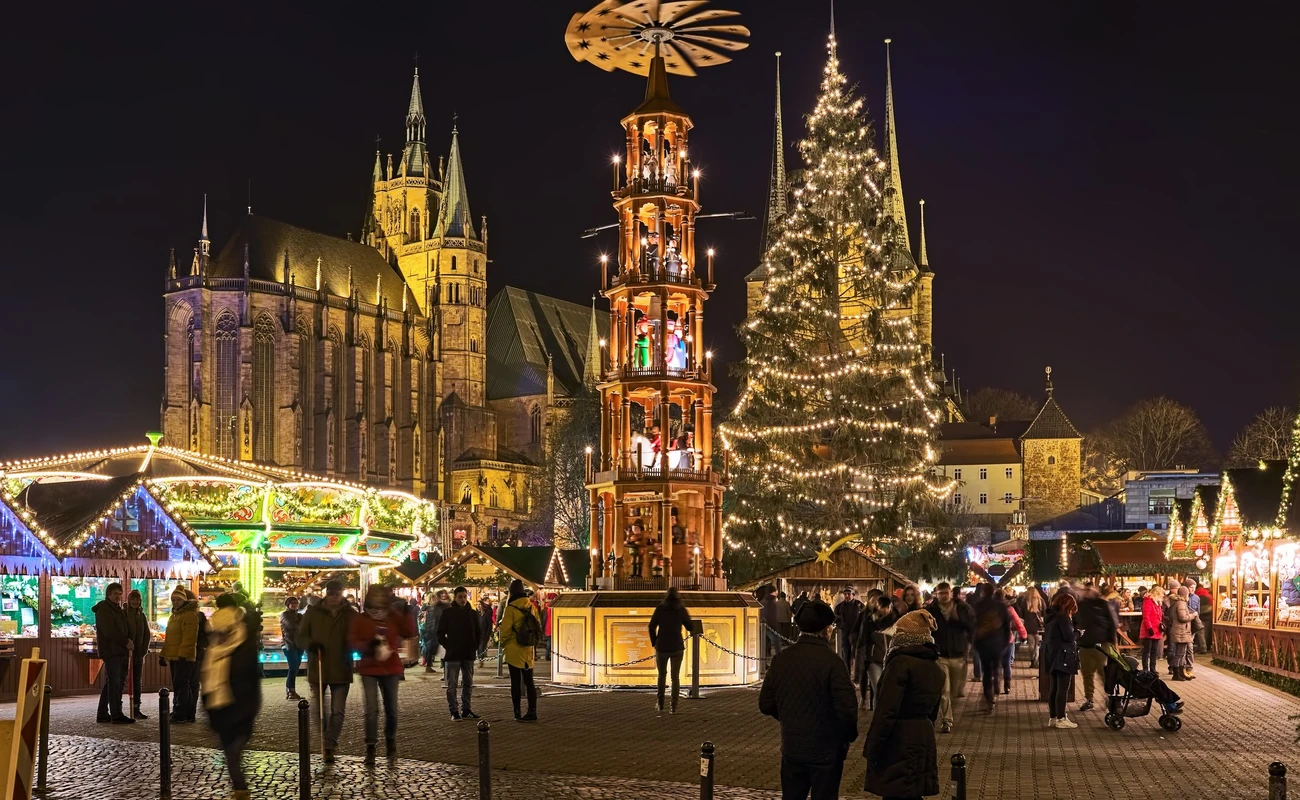 Erfurt, Germany. Christmas pyramid at Christmas market on Domplatz (Cathedral Square) in night. St Mary's Cathedral is visible in the background. Church of St Severus is hidden by the Christmas tree.